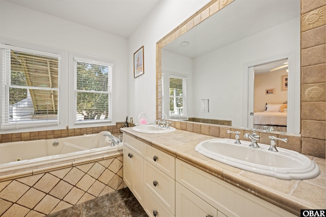 ensuite bathroom featuring double vanity, connected bathroom, a bath, and a sink