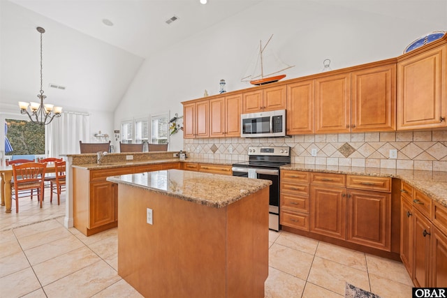 kitchen featuring visible vents, a center island, appliances with stainless steel finishes, a peninsula, and light stone countertops