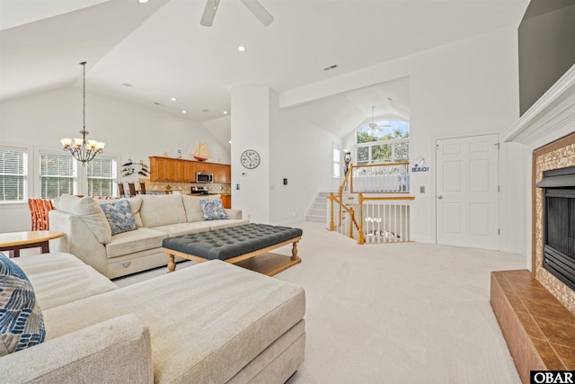 carpeted living area with a tiled fireplace, ceiling fan with notable chandelier, a healthy amount of sunlight, and stairs