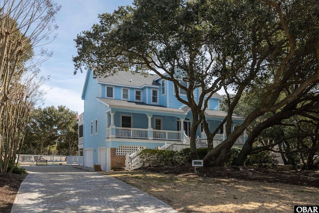 view of front of house featuring stairway, decorative driveway, covered porch, and roof with shingles