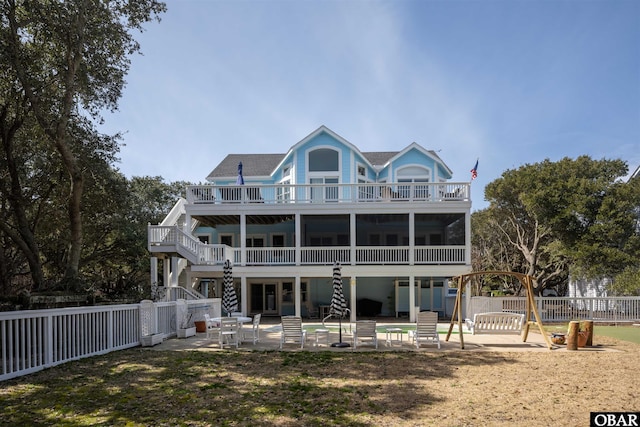 rear view of property with stairs, a balcony, a patio area, and a fenced backyard