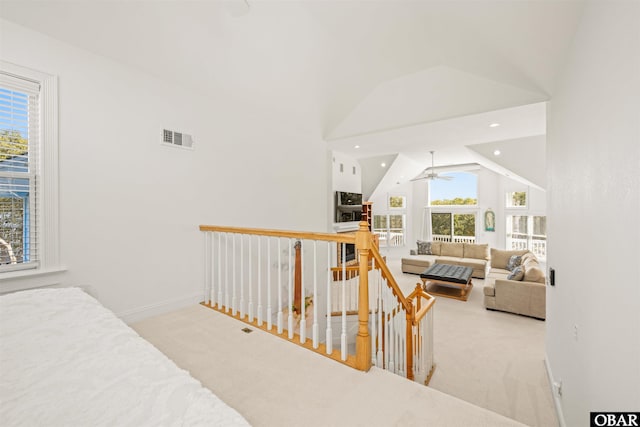 hall featuring a wealth of natural light, an upstairs landing, visible vents, and carpet floors