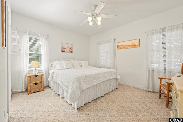 bedroom with light colored carpet, baseboards, and ceiling fan