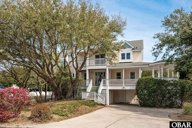 view of front of house with a balcony, covered porch, stairs, and concrete driveway