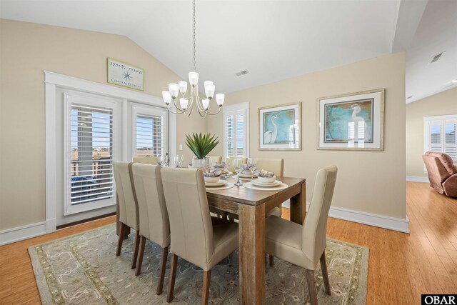 dining space with a notable chandelier, plenty of natural light, lofted ceiling, and wood finished floors