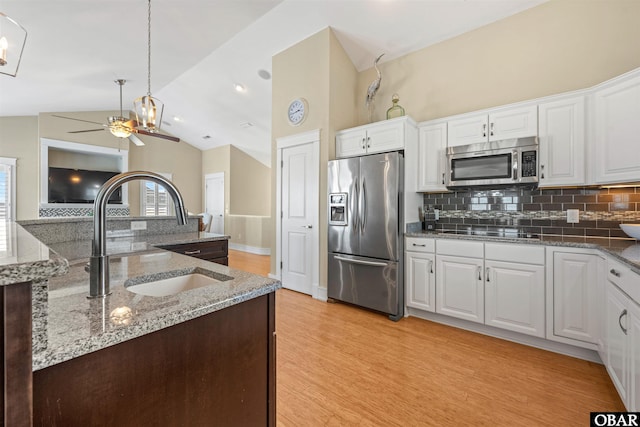 kitchen featuring a sink, vaulted ceiling, decorative backsplash, and stainless steel appliances