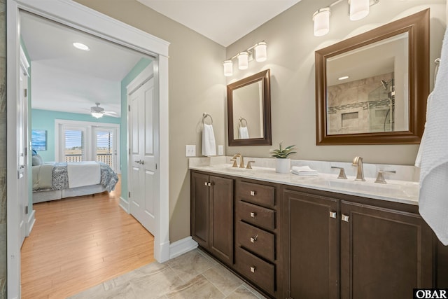 bathroom with a sink, tiled shower, double vanity, and ensuite bathroom