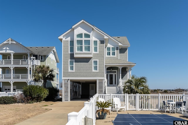 coastal inspired home featuring a carport, fence, driveway, and a shingled roof