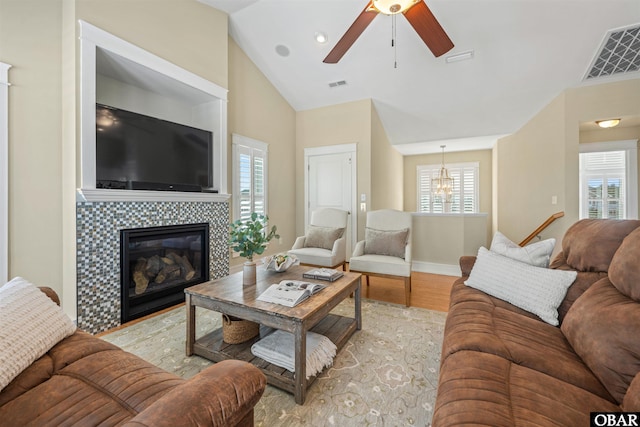 living room featuring vaulted ceiling, light wood-style floors, visible vents, and a tile fireplace