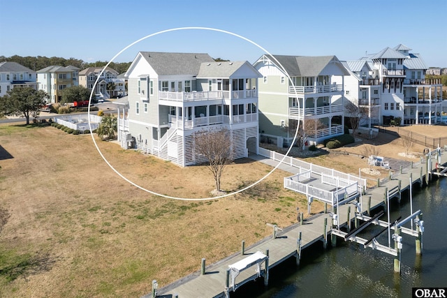 rear view of property with a lawn, a residential view, a water view, and boat lift