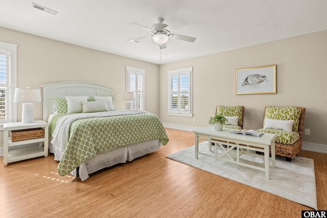 bedroom featuring visible vents, ceiling fan, baseboards, and wood finished floors