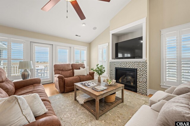 living room featuring a wealth of natural light, visible vents, lofted ceiling, and a fireplace