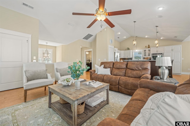 living area featuring light wood-style flooring, a ceiling fan, visible vents, and high vaulted ceiling