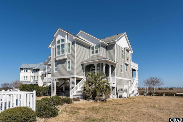 view of front of home with stairs, a front lawn, fence, and a shingled roof