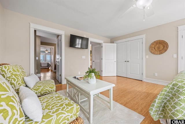 living room with a ceiling fan, wood finished floors, and baseboards