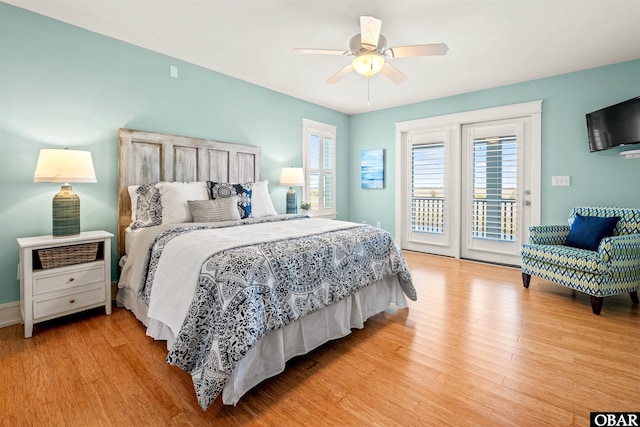 bedroom with access to outside, multiple windows, and light wood-type flooring