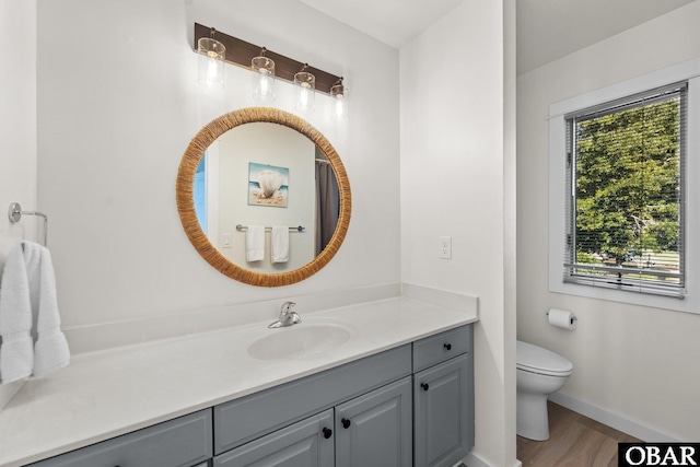 bathroom with baseboards, vanity, toilet, and wood finished floors