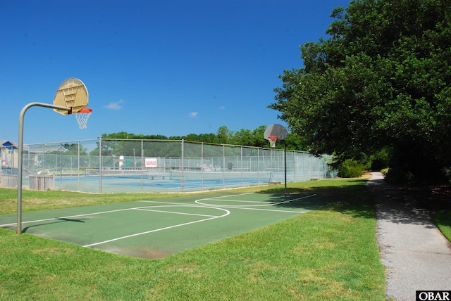 view of sport court with a tennis court, community basketball court, a lawn, and fence