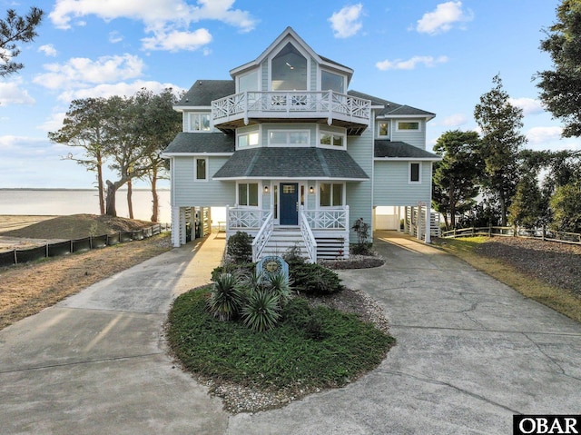 view of front of house with a porch, a shingled roof, stairs, concrete driveway, and a carport