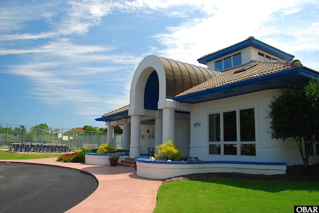 view of front of property featuring stucco siding, a front yard, fence, and a tiled roof