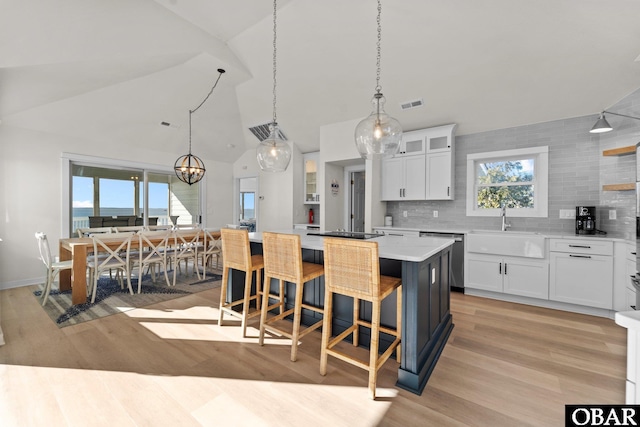 kitchen with glass insert cabinets, white cabinetry, light countertops, and a center island