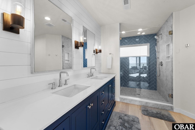 bathroom with wood finished floors, a sink, visible vents, and a shower stall