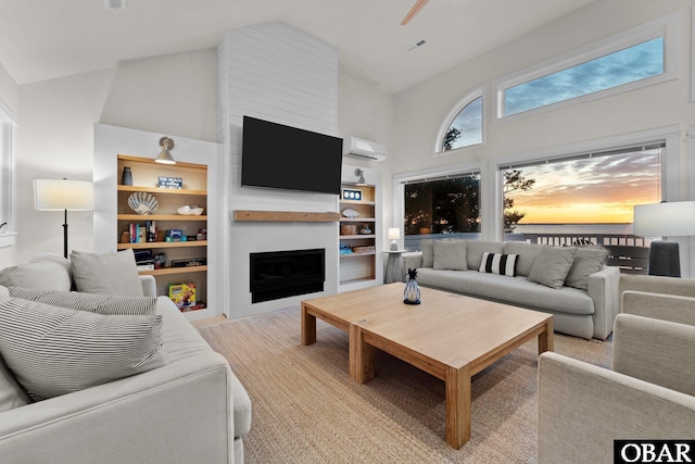 living area featuring a fireplace, high vaulted ceiling, built in features, and a wall mounted AC