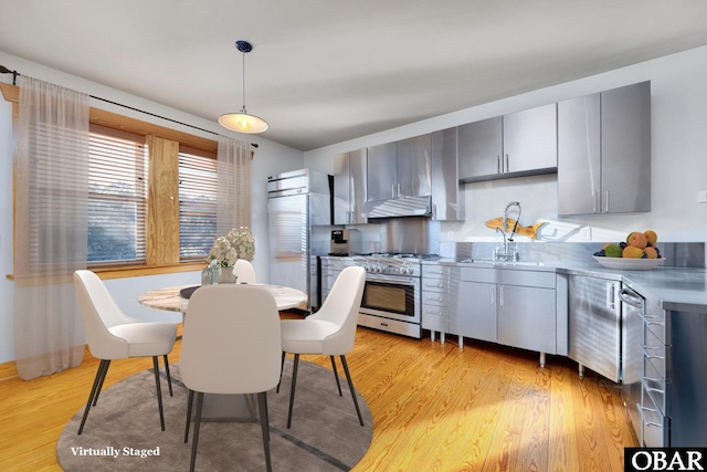 kitchen featuring light wood-style flooring, gray cabinetry, a sink, stainless steel range, and pendant lighting