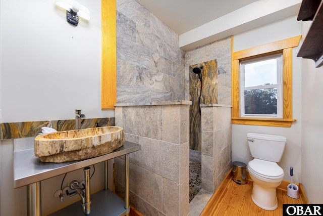 full bathroom featuring a walk in shower, toilet, wood finished floors, a sink, and baseboards