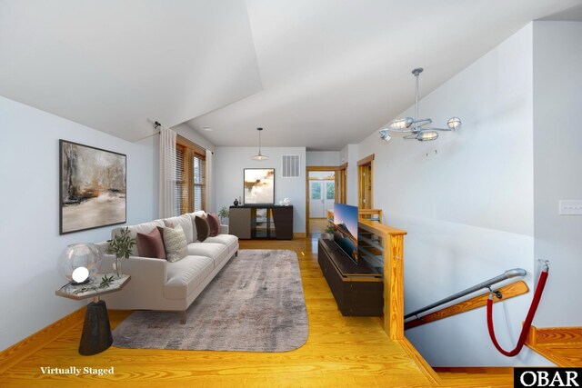 living area featuring light wood-style floors, plenty of natural light, visible vents, and vaulted ceiling