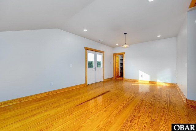 empty room featuring lofted ceiling, recessed lighting, baseboards, french doors, and light wood-type flooring