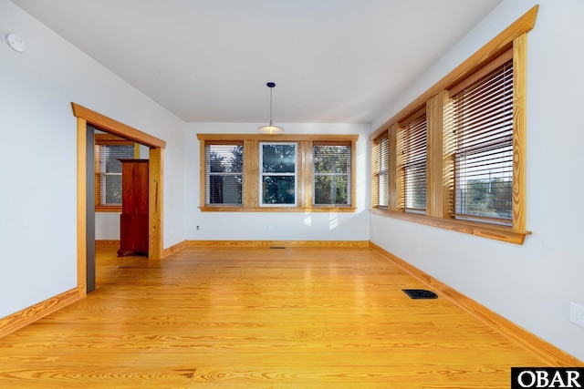 unfurnished room featuring light wood-type flooring, baseboards, and visible vents