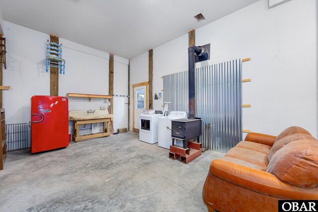 living room with a wood stove, unfinished concrete flooring, and washing machine and clothes dryer