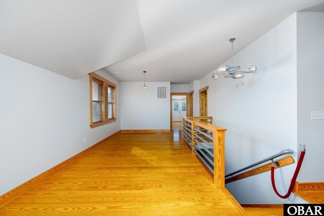 hall featuring visible vents, light wood-style flooring, and baseboards