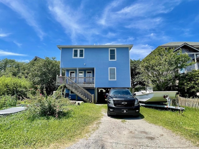 back of house featuring dirt driveway, covered porch, and stairs