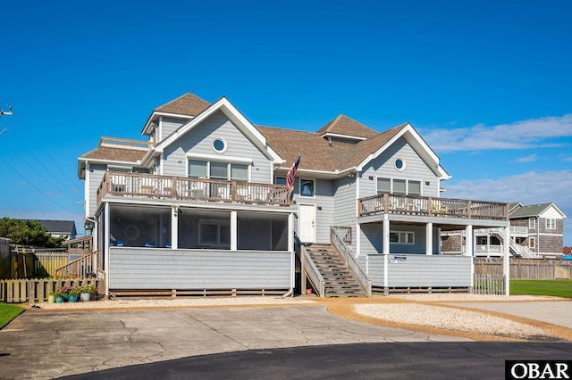 view of front of property featuring a shingled roof, stairs, and fence