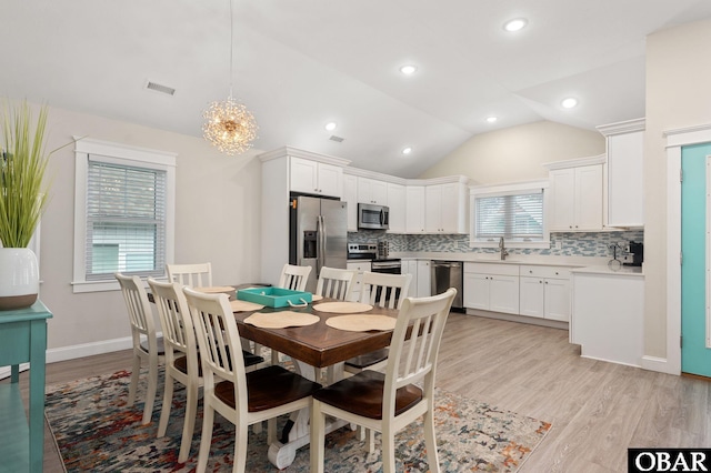 dining space featuring lofted ceiling, visible vents, light wood-style flooring, a chandelier, and baseboards