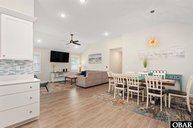 dining area with lofted ceiling, light wood-style flooring, recessed lighting, and ceiling fan with notable chandelier