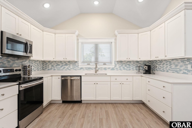 kitchen with appliances with stainless steel finishes, lofted ceiling, light countertops, and a sink