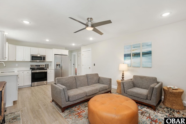 living area featuring light wood finished floors, ceiling fan, baseboards, and recessed lighting