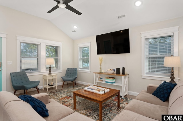 living room featuring lofted ceiling, visible vents, baseboards, and wood finished floors