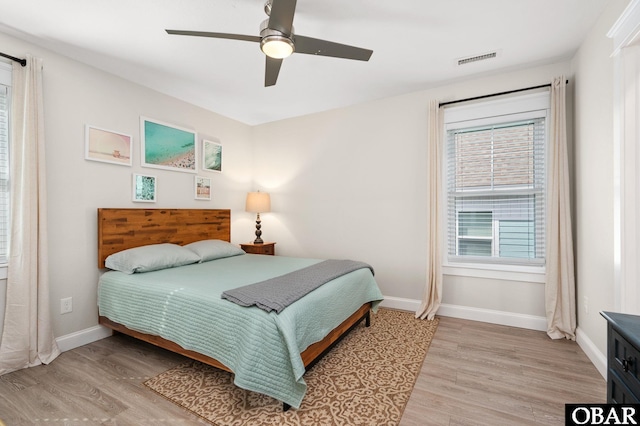 bedroom featuring light wood-style floors, baseboards, visible vents, and a ceiling fan