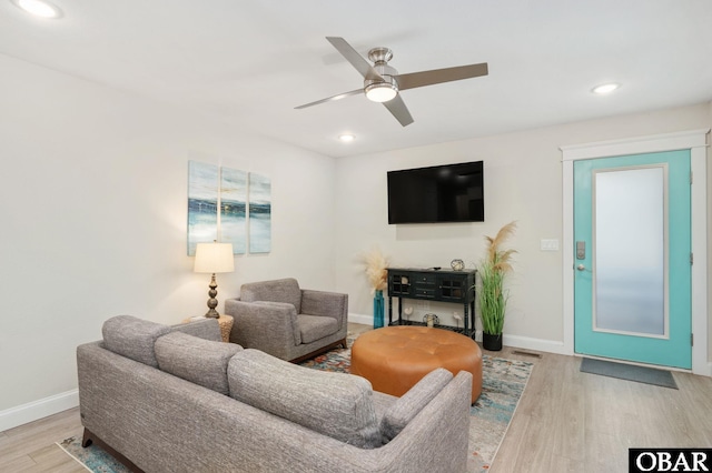 living area featuring ceiling fan, baseboards, and wood finished floors