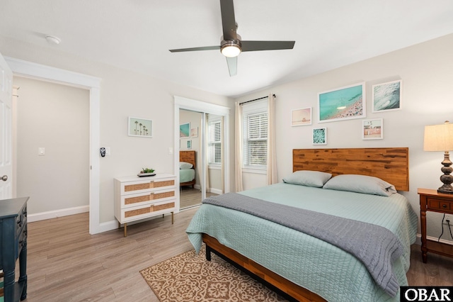 bedroom featuring light wood-style flooring, baseboards, ceiling fan, and a closet