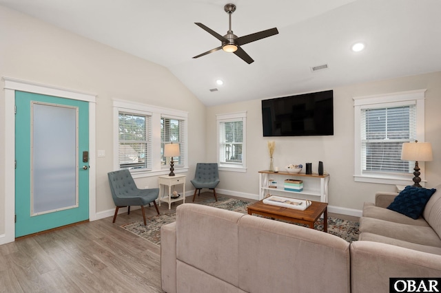 living area featuring lofted ceiling, visible vents, ceiling fan, wood finished floors, and baseboards