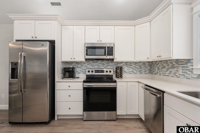 kitchen with appliances with stainless steel finishes, light countertops, visible vents, and tasteful backsplash