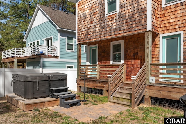 back of property featuring a shingled roof and a hot tub