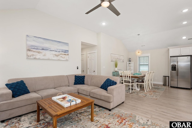 living room featuring vaulted ceiling, ceiling fan with notable chandelier, light wood-type flooring, and recessed lighting