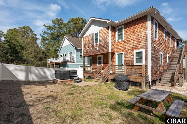 rear view of house featuring a lawn, stairway, a hot tub, a fenced backyard, and a wooden deck