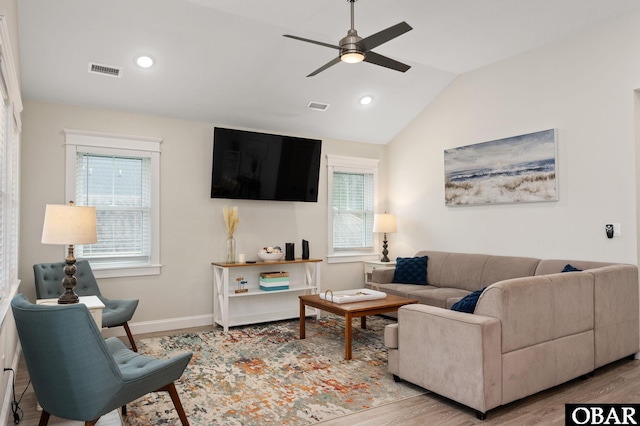 living room with lofted ceiling, light wood finished floors, visible vents, and baseboards